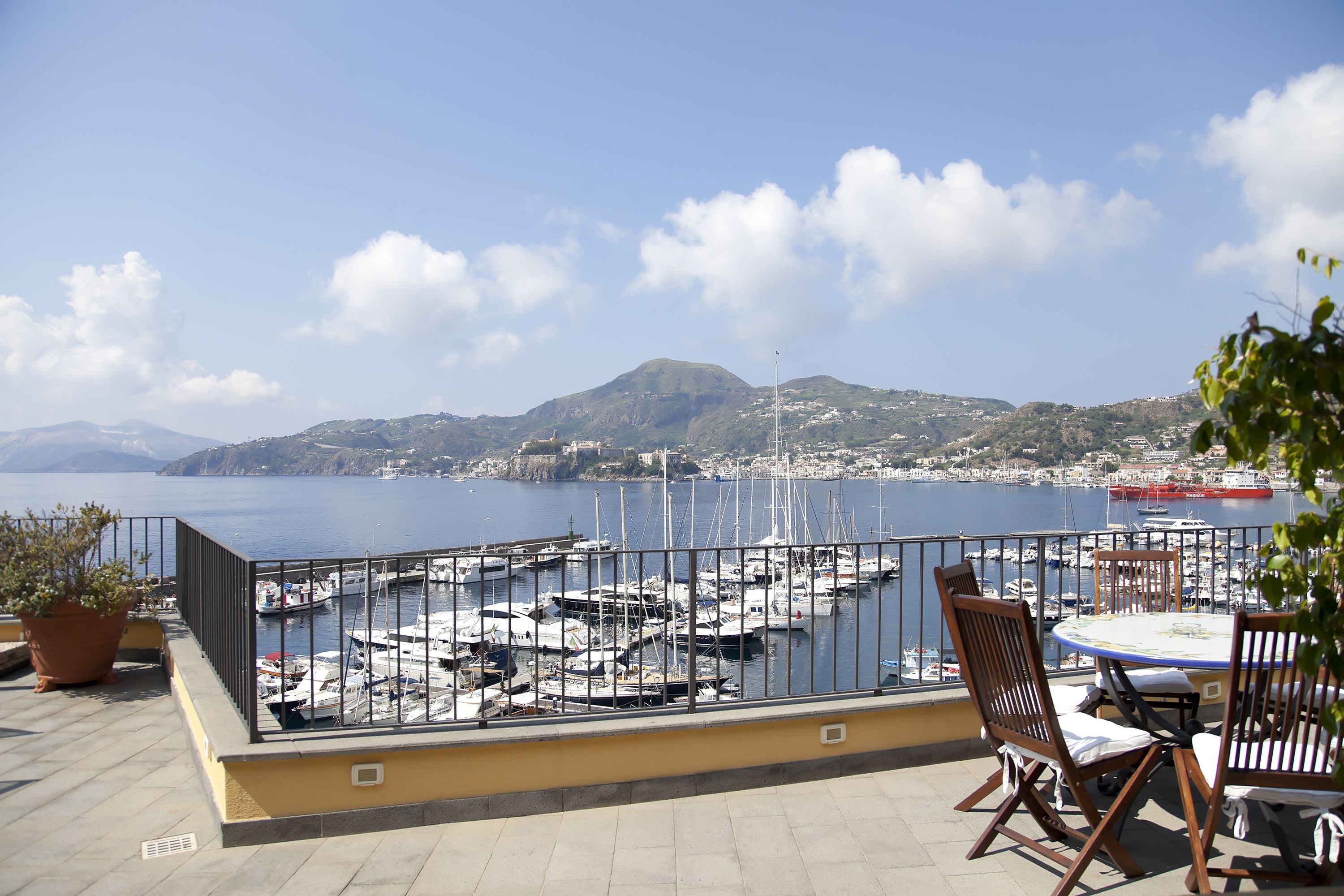 A terrace with a view of a marina, boats, and a distant mountain.