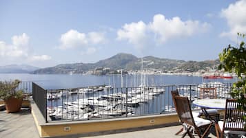 A terrace with a view of a marina, boats, and a distant mountain.