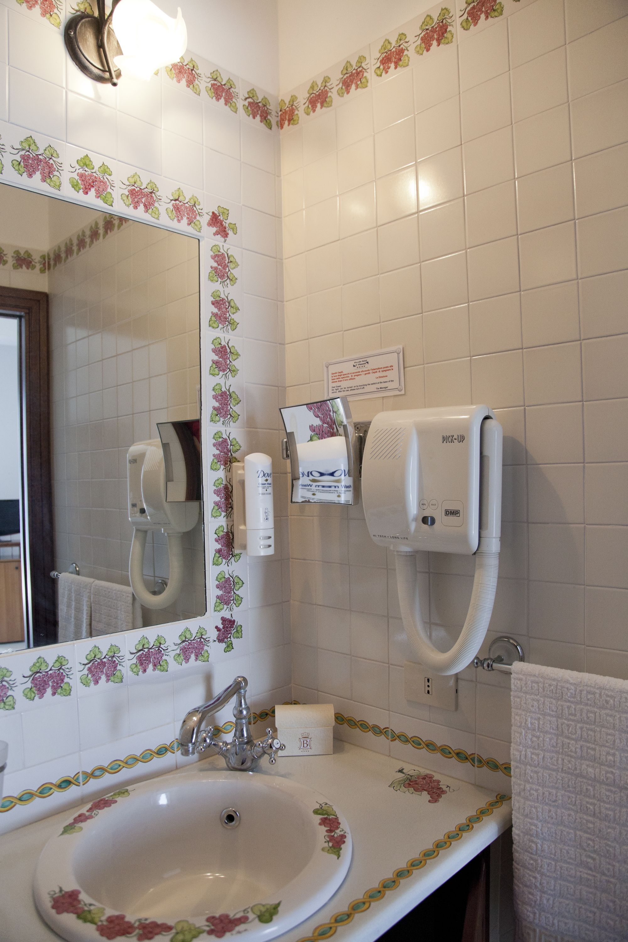 A bathroom with a sink, mirror, and hand dryer.