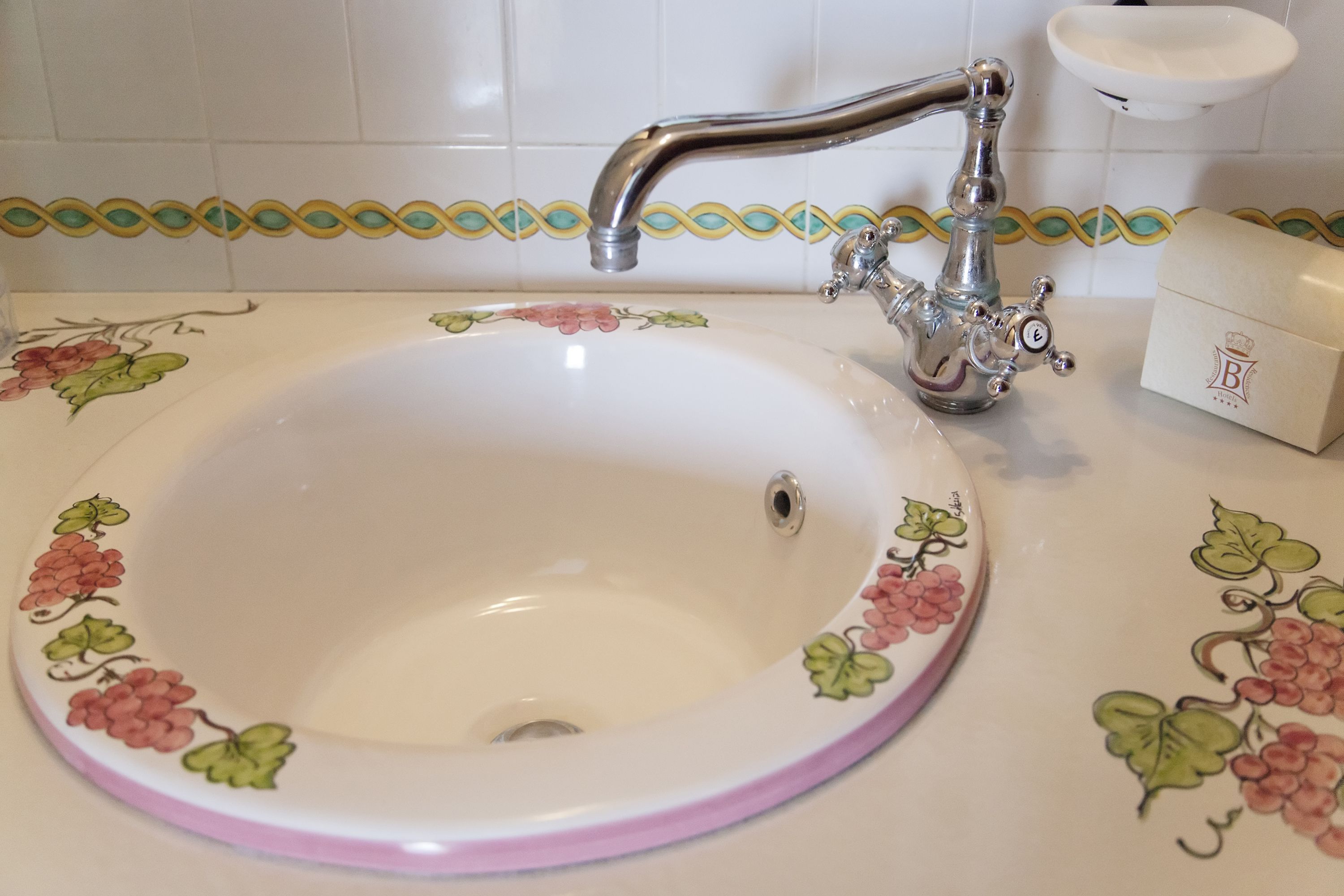 Ein Waschbecken mit floralem Dekor, einem Wasserhahn und einer Seifenschale.