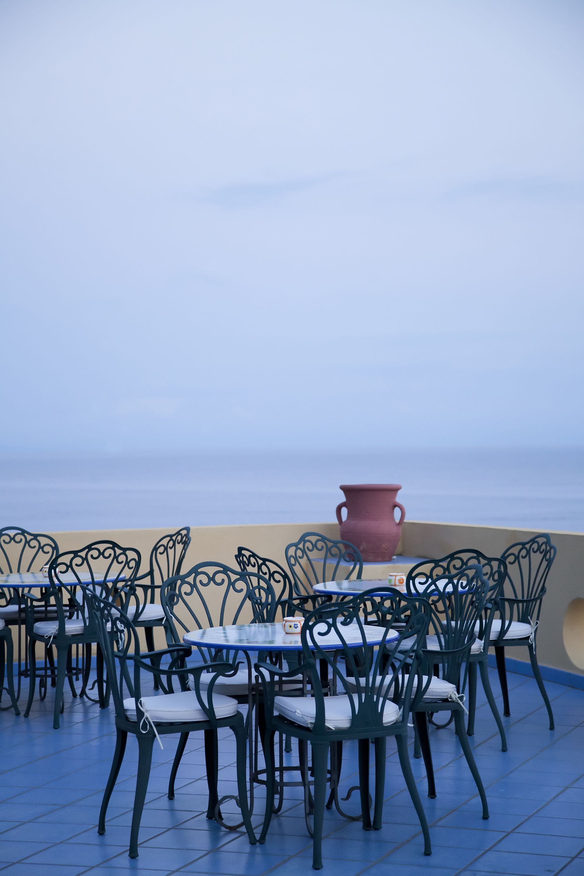 Outdoor dining tables and chairs with a view of the sea.
