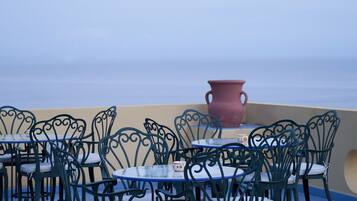 Outdoor dining tables and chairs with a view of the sea.