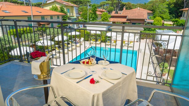 Mesa para dos con vista a una piscina y casas circundantes.