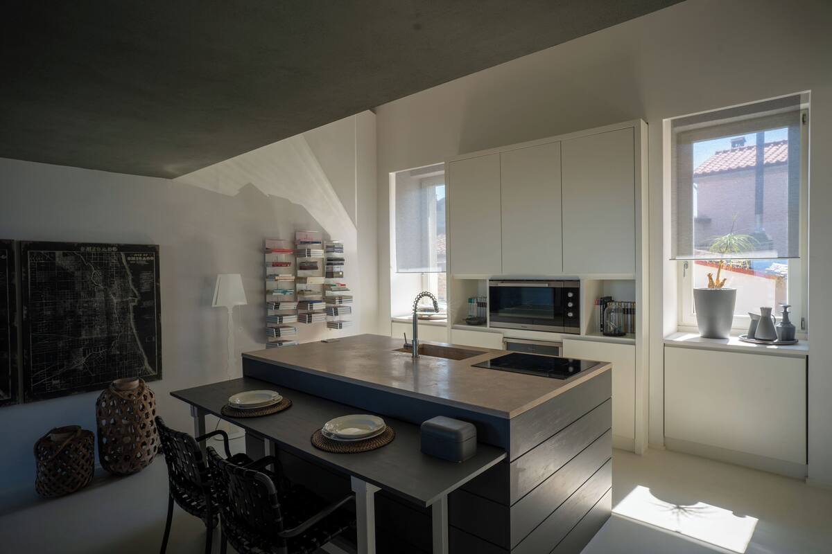 Eine moderne Küche mit Kochinsel, weißen Schränken und Blick ins Freie.
