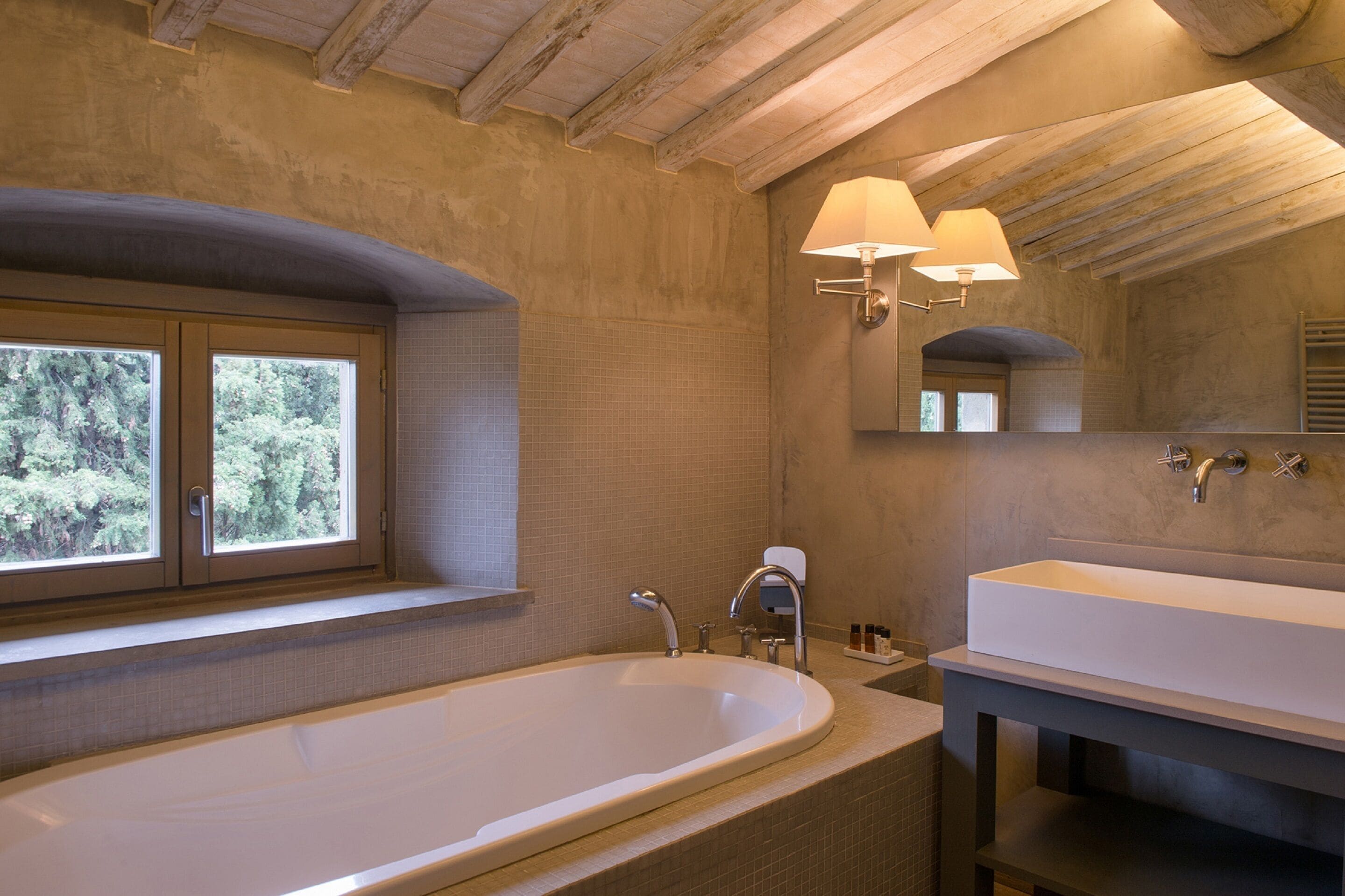 A bathroom with a large bathtub, a window, a sink, and a mirror.