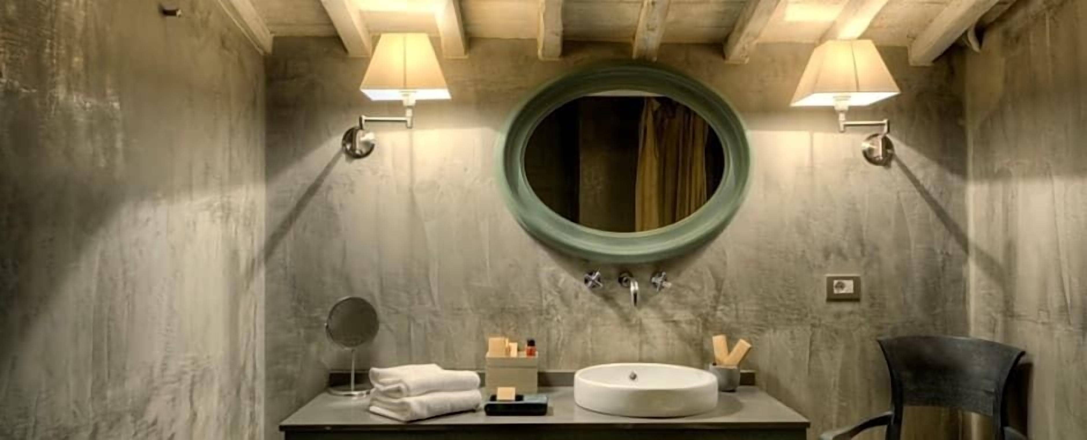 Ein Badezimmer mit einem runden Spiegel, einem Waschbecken und zwei Wandleuchten.