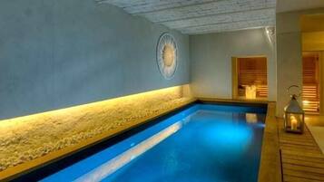 Un'area benessere con piscina blu, una parete in pietra e un pontile in legno.