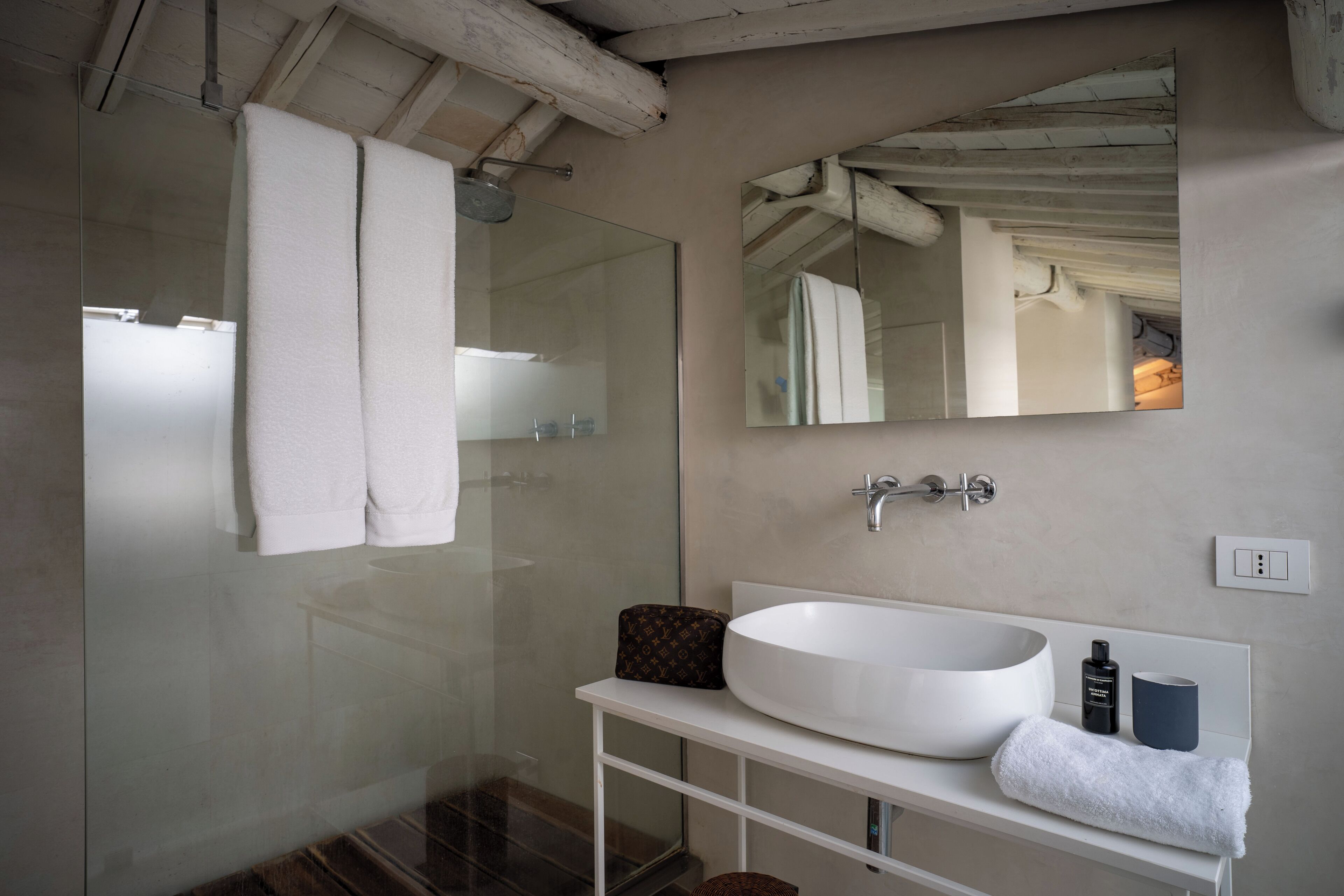 Ein modernes Badezimmer mit einem großen weißen Waschbecken, einem Spiegel und einer Duschkabine aus Glas.