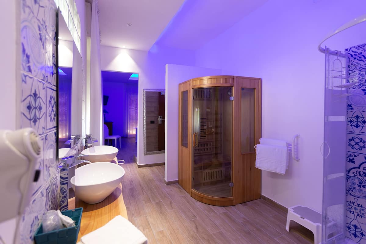 A modern bathroom with a large mirror, two sinks, a shower enclosure, and a towel rack.