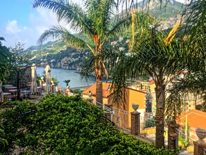 Una vista sulla costa con terrazza, palme e edifici sullo sfondo.