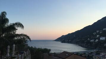 Vista costera con cielo despejado, mar tranquilo y edificios en una colina.