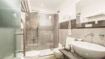 Un baño moderno con ducha de vidrio, bañera independiente, inodoro y tocador con lavamanos.