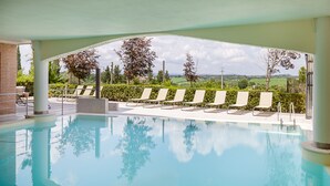 Una piscina cubierta con sillones de descanso y vistas al campo.