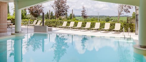 Una piscina cubierta, una piscina al aire libre de temporada, sombrillas