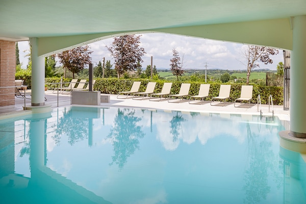 Una piscina techada, una piscina al aire libre de temporada, sombrillas