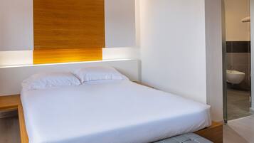 Camera da letto moderna con un letto grande, una parete decorativa in legno e una porta doccia in vetro.