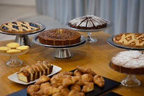 Una variedad de postres a la vista, incluyendo tartas, pasteles y productos de pastelería, dispuestos en soportes metálicos.