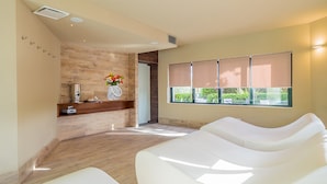 Un cuarto de spa con mostrador de recepción, una silla de masaje y una ventana con persianas.