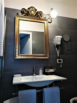 A bathroom with a large ornate mirror, a white sink, a hairdryer, and a towel rack. - Antica Venezia (Venice)