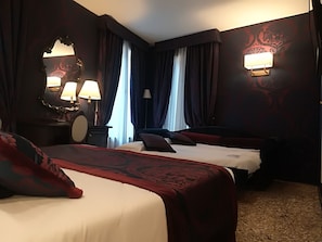 A hotel room with two beds, a large mirror, two wall-mounted lamps, and a carpeted floor.