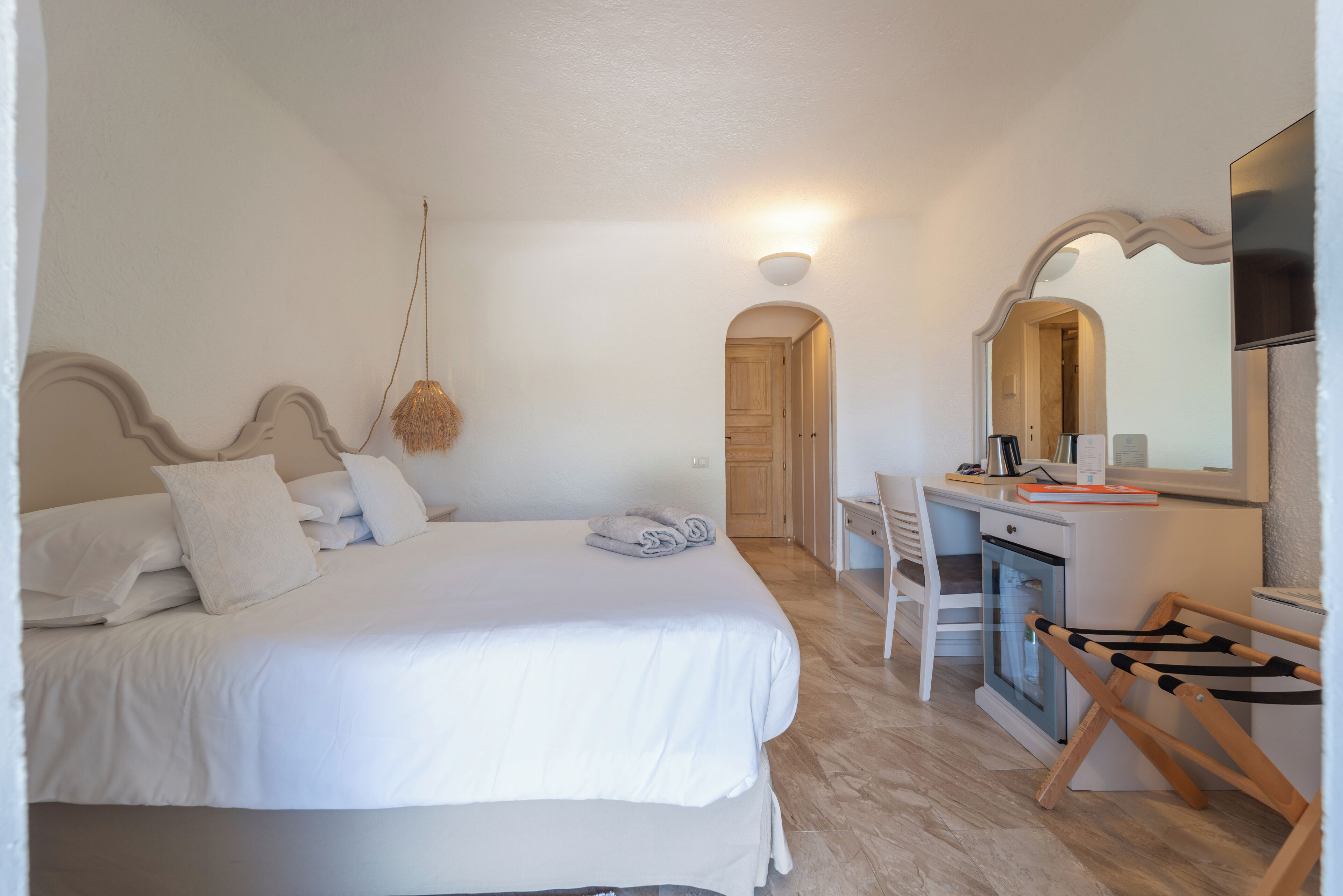 A bedroom with a bed, desk, and a mirror.