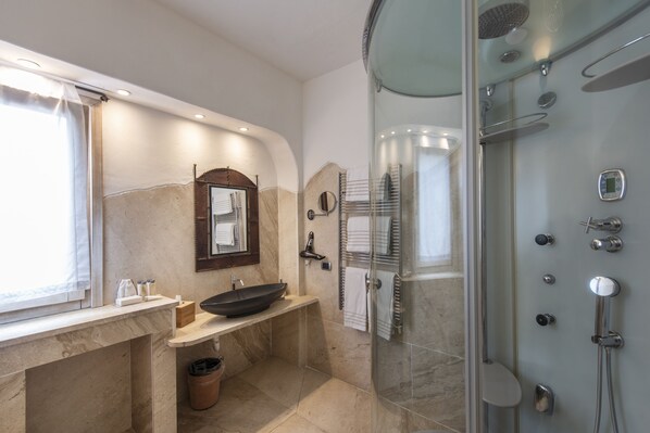 A modern bathroom with a large sink, a glass-enclosed shower, and a marble-tiled floor. - Hotel Balocco (Arzachena)