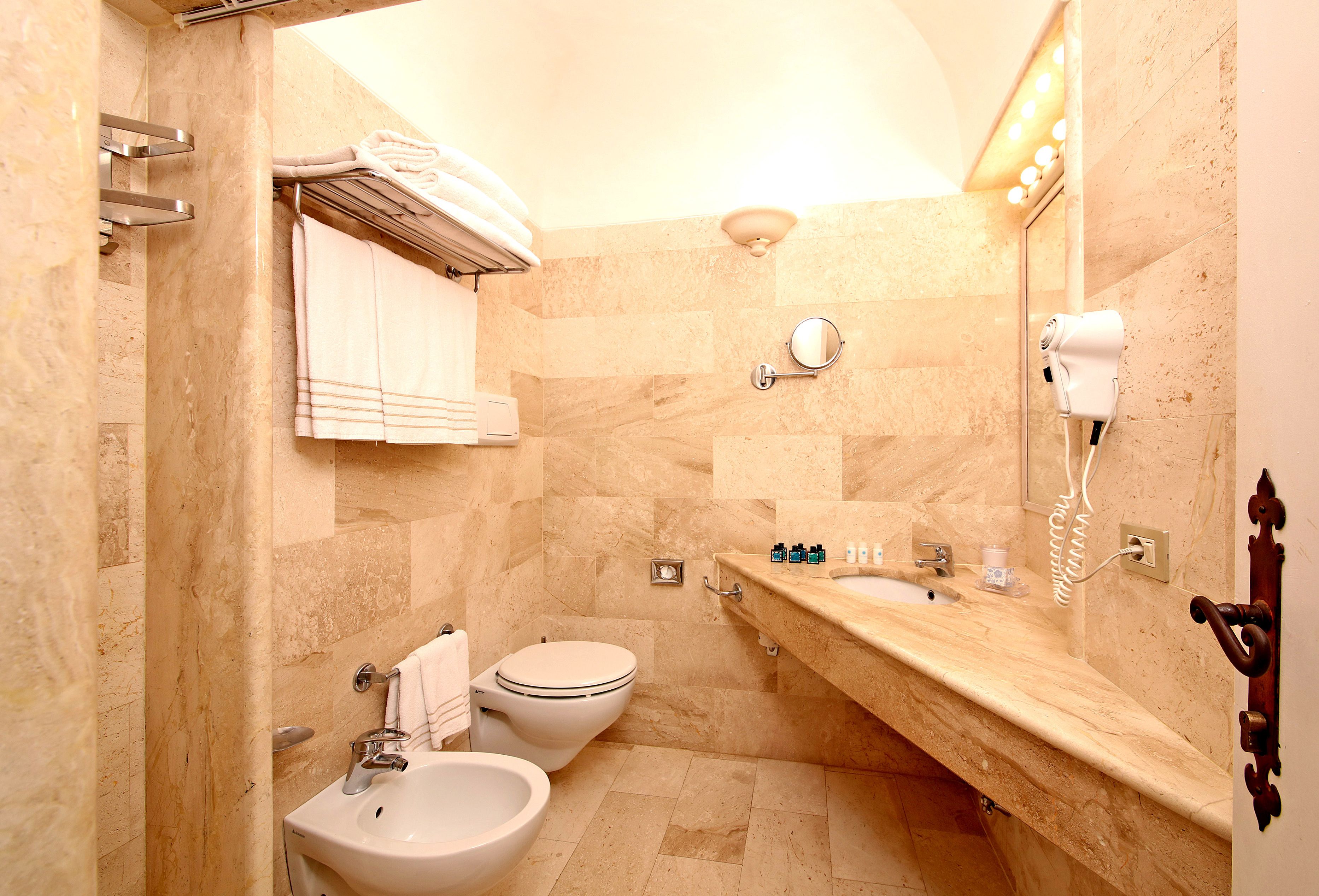 A bathroom with a sink, bidet, and towel rack.