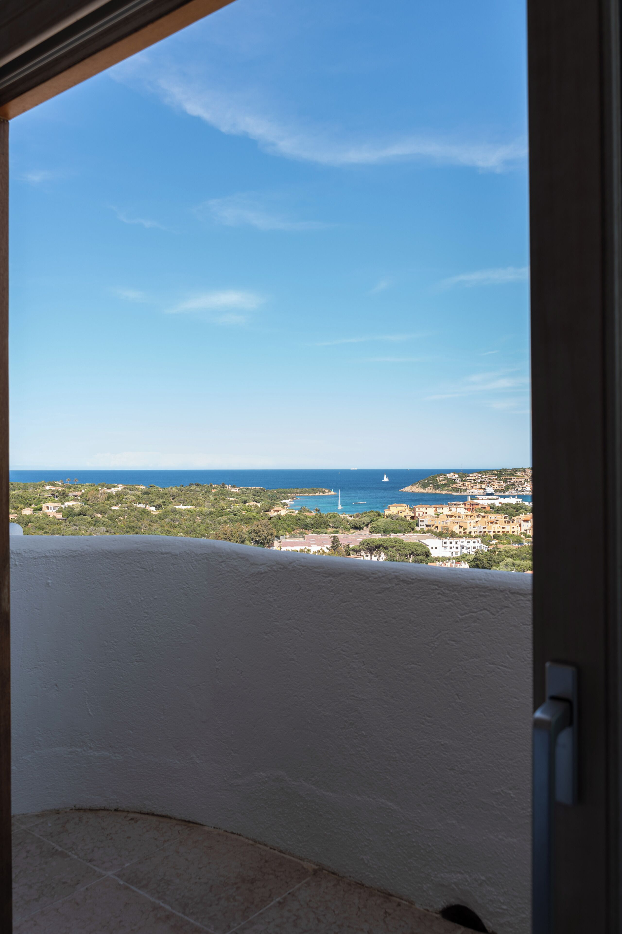 Een balkon met uitzicht op zee en verre gebouwen.