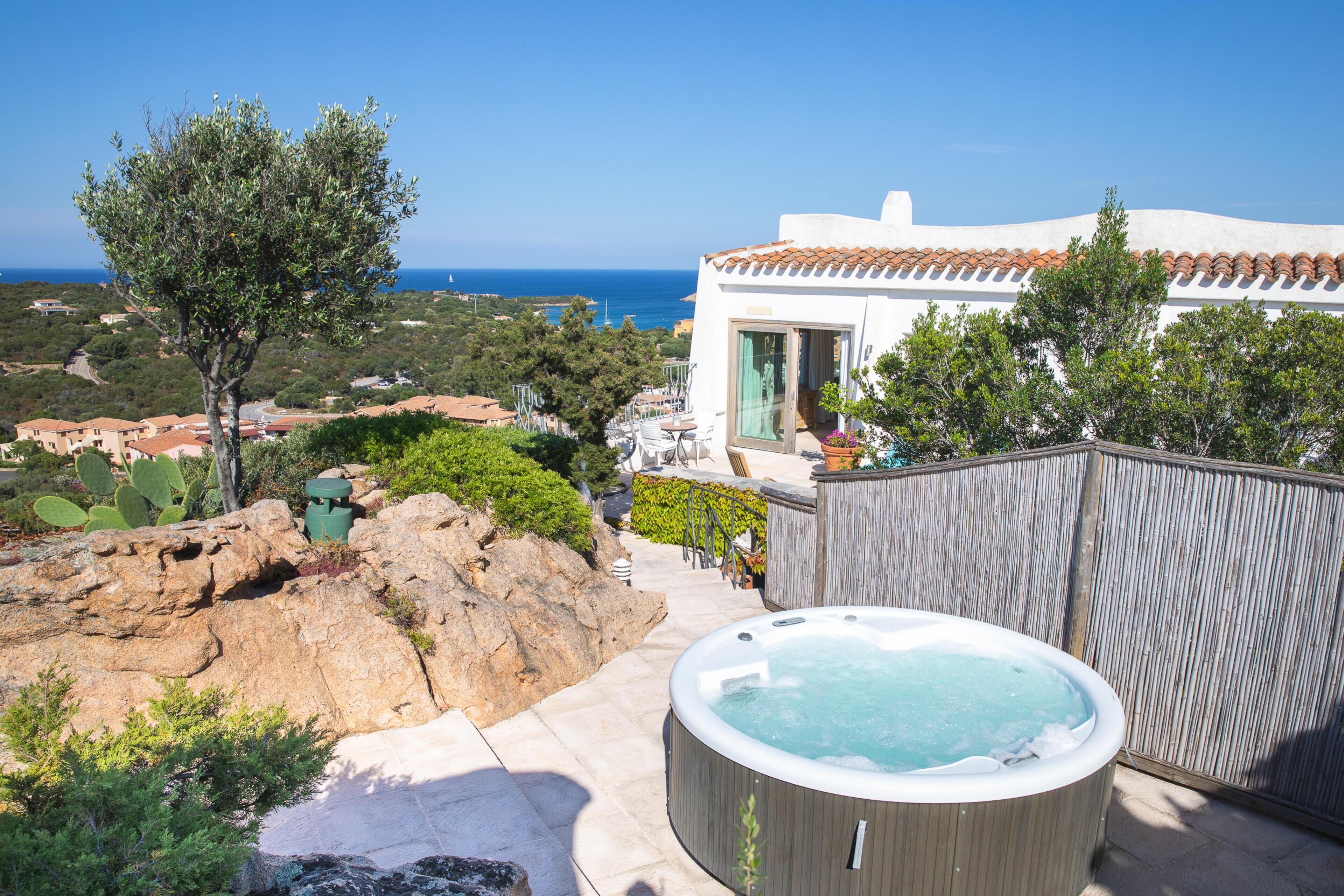 A hot tub in a backyard with a view of the sea and a building with a tiled roof.