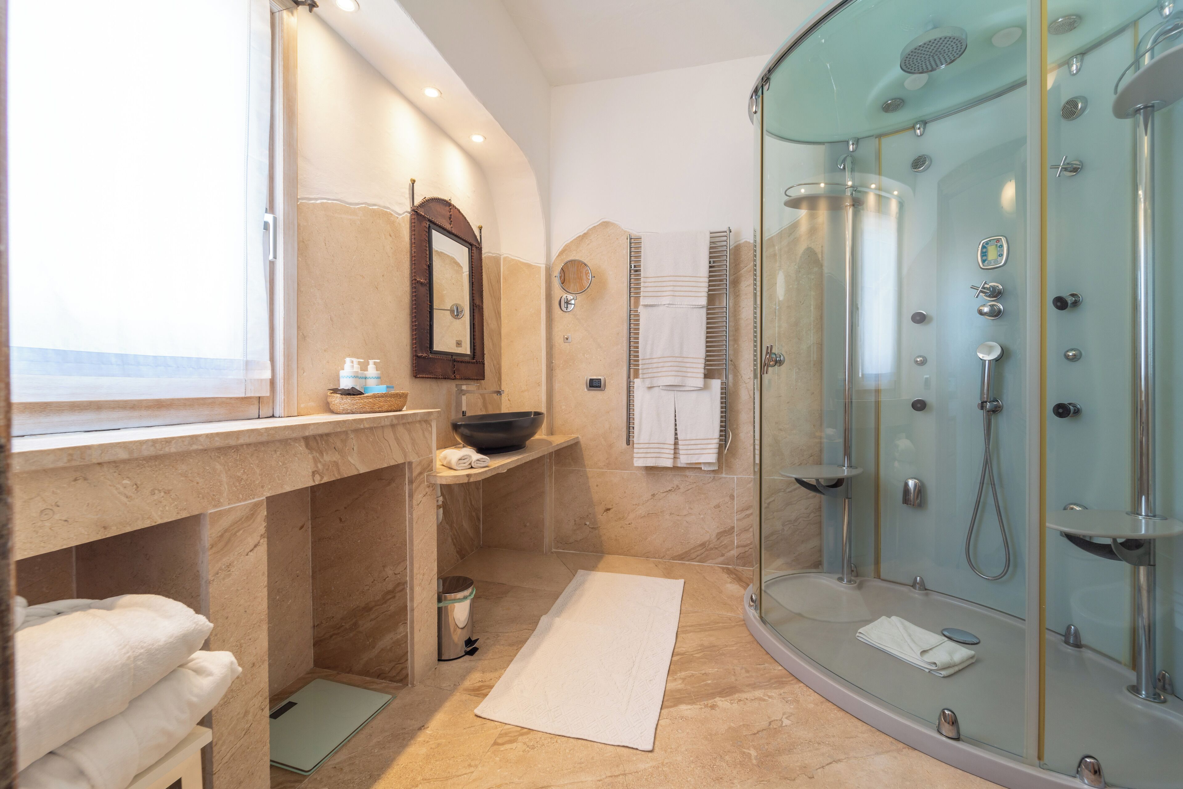 Un baño moderno con ducha de vidrio, tocador de mármol y un espejo grande.