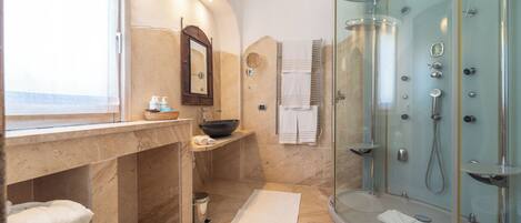 Un baño moderno con ducha de vidrio, tocador de mármol y un espejo grande.