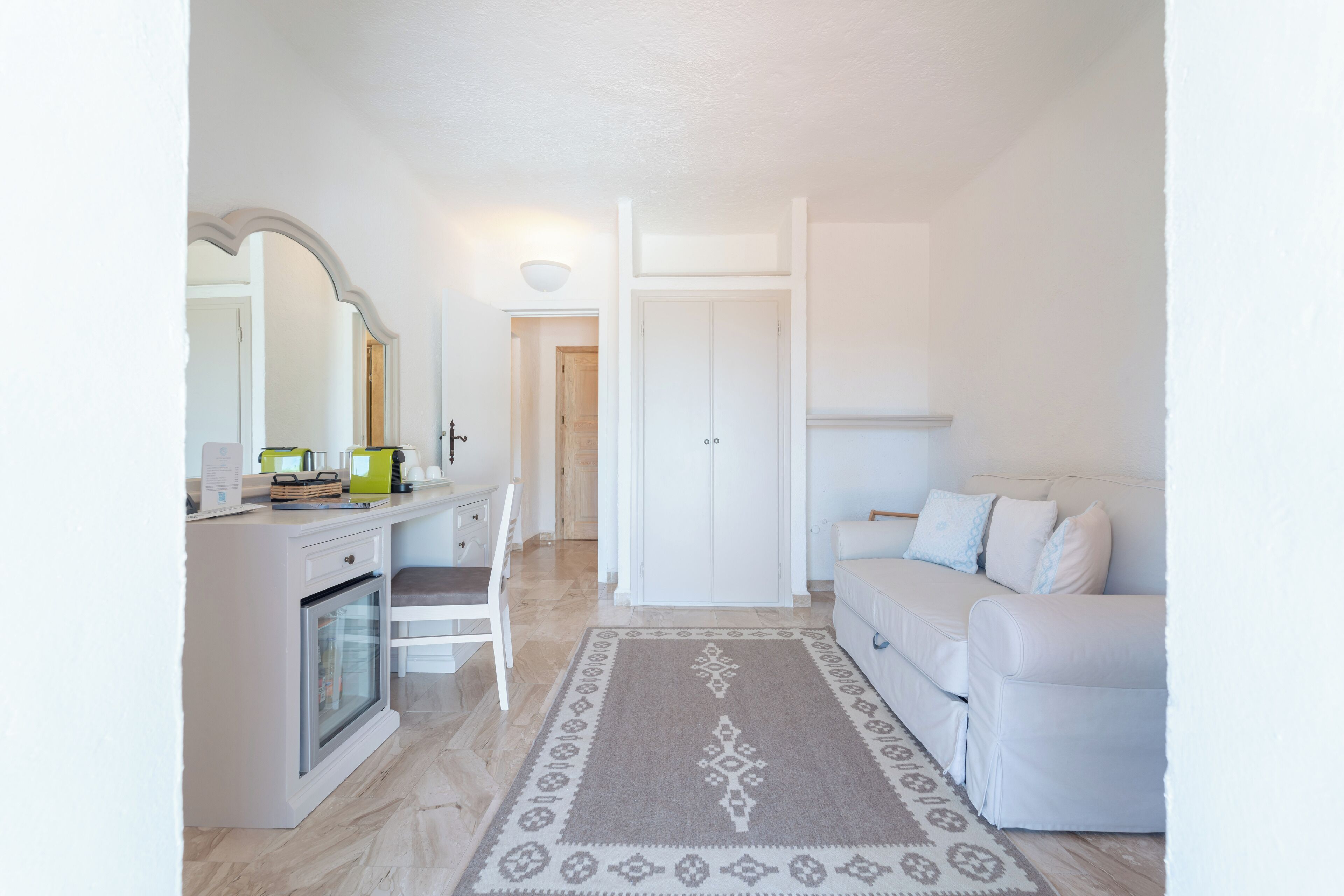 A modern, well-lit room with a kitchenette, a dining area, and a seating area with a sofa and a rug.