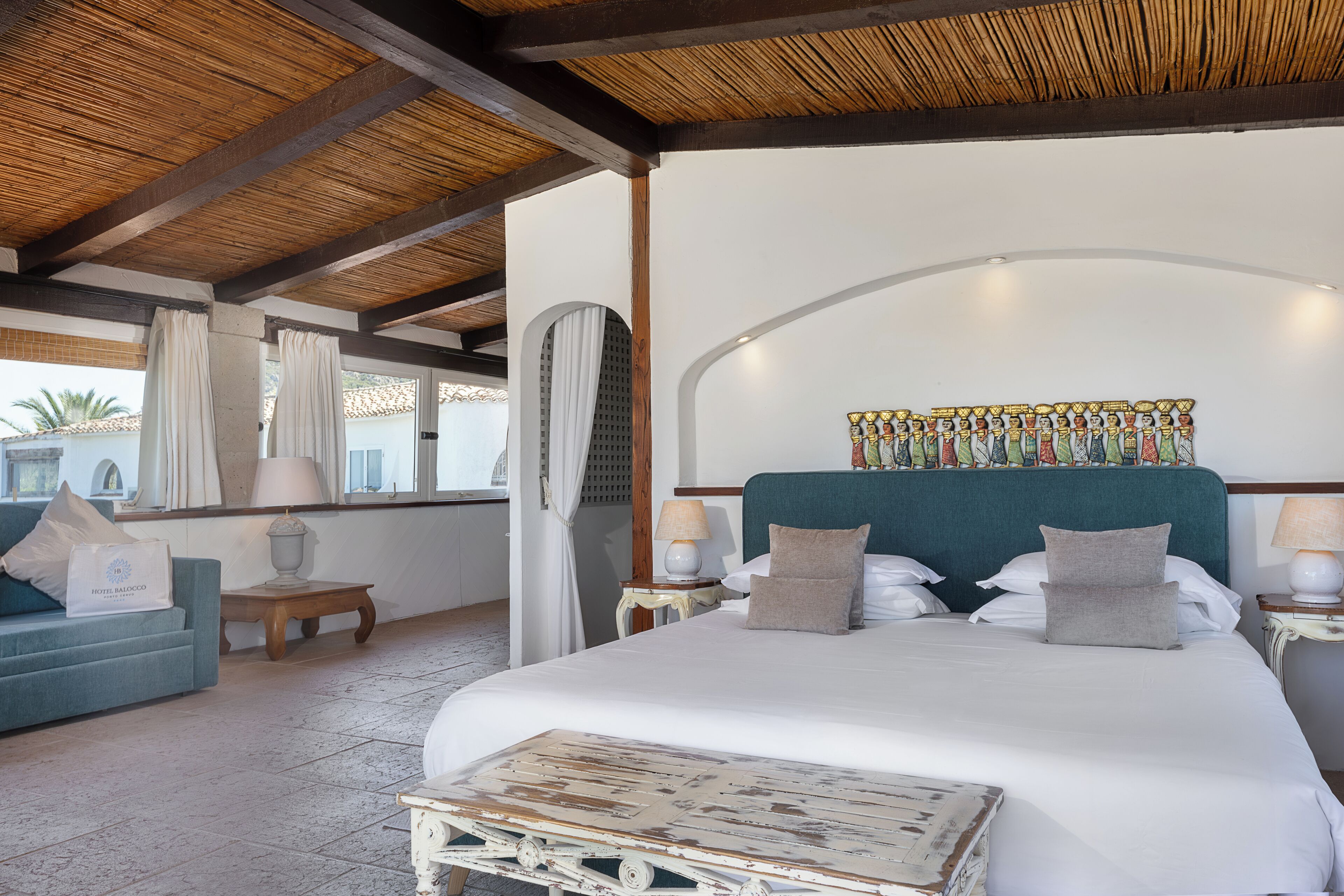 A spacious bedroom with a large bed, a wooden headboard, and a view of the outdoors.