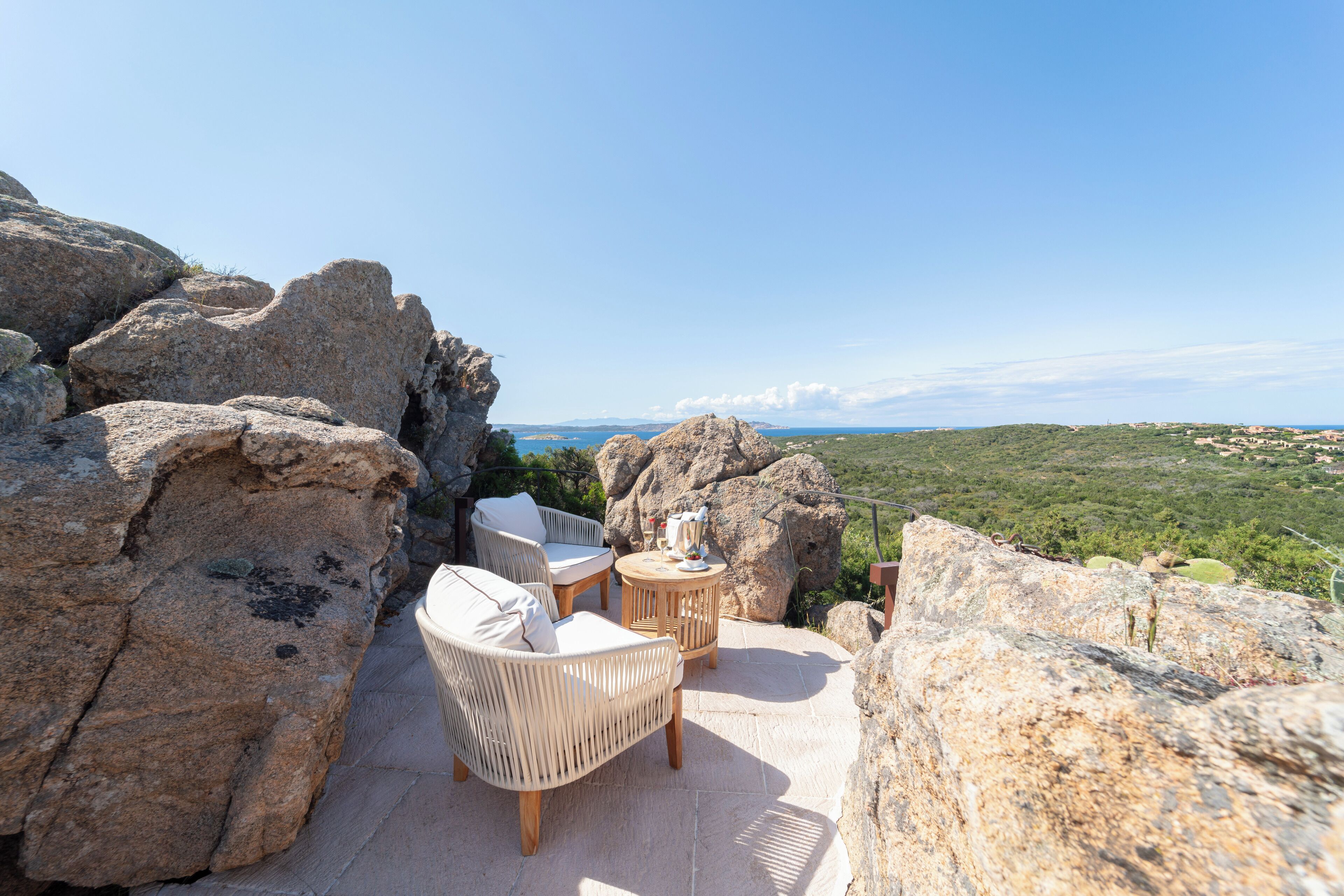 Un patio con muebles de mimbre y una mesa, con vistas a un paisaje pintoresco.