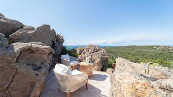 Un patio con muebles de mimbre y una mesa, con vistas a un paisaje pintoresco.