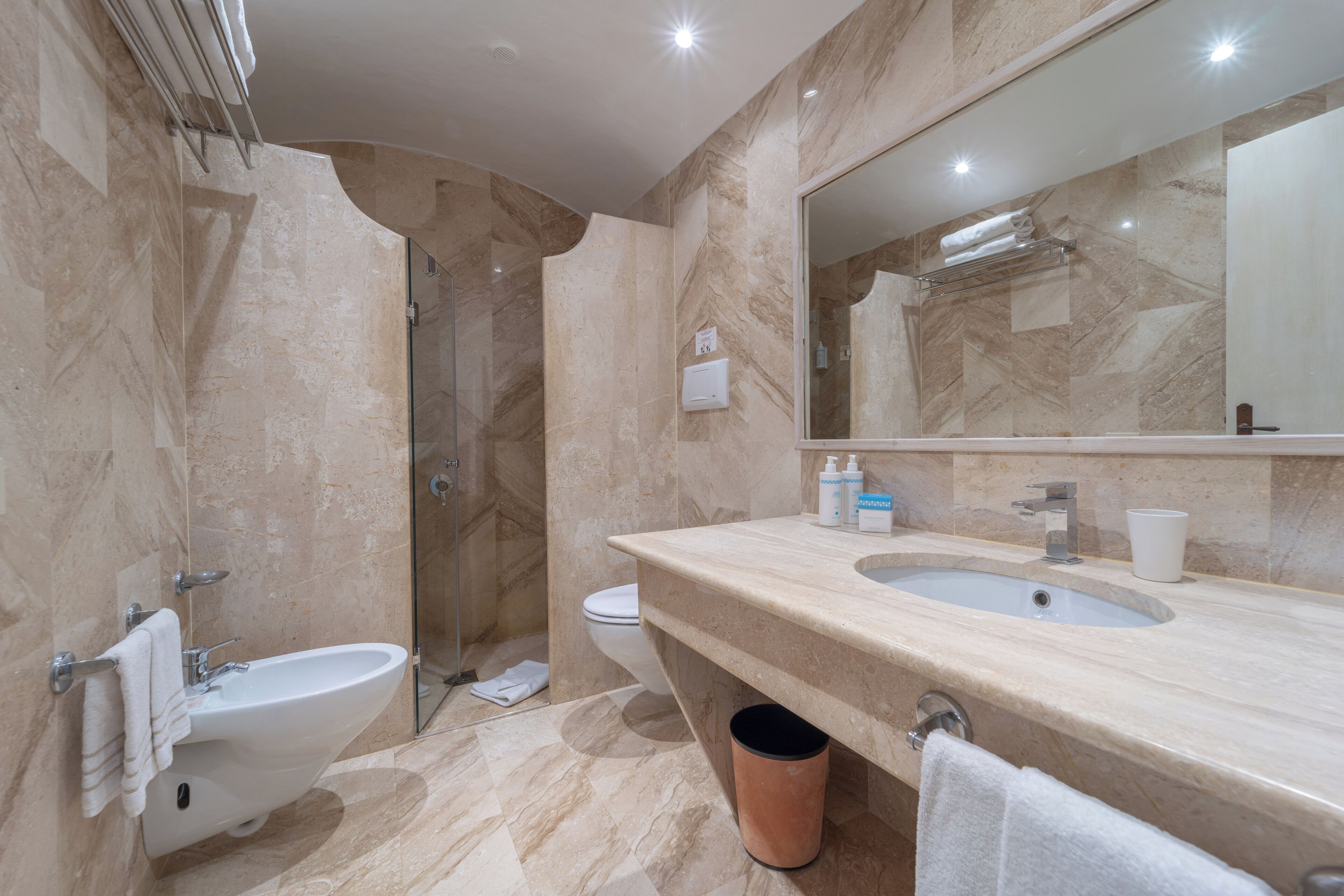 A modern bathroom with a bidet, sink, and large mirror.
