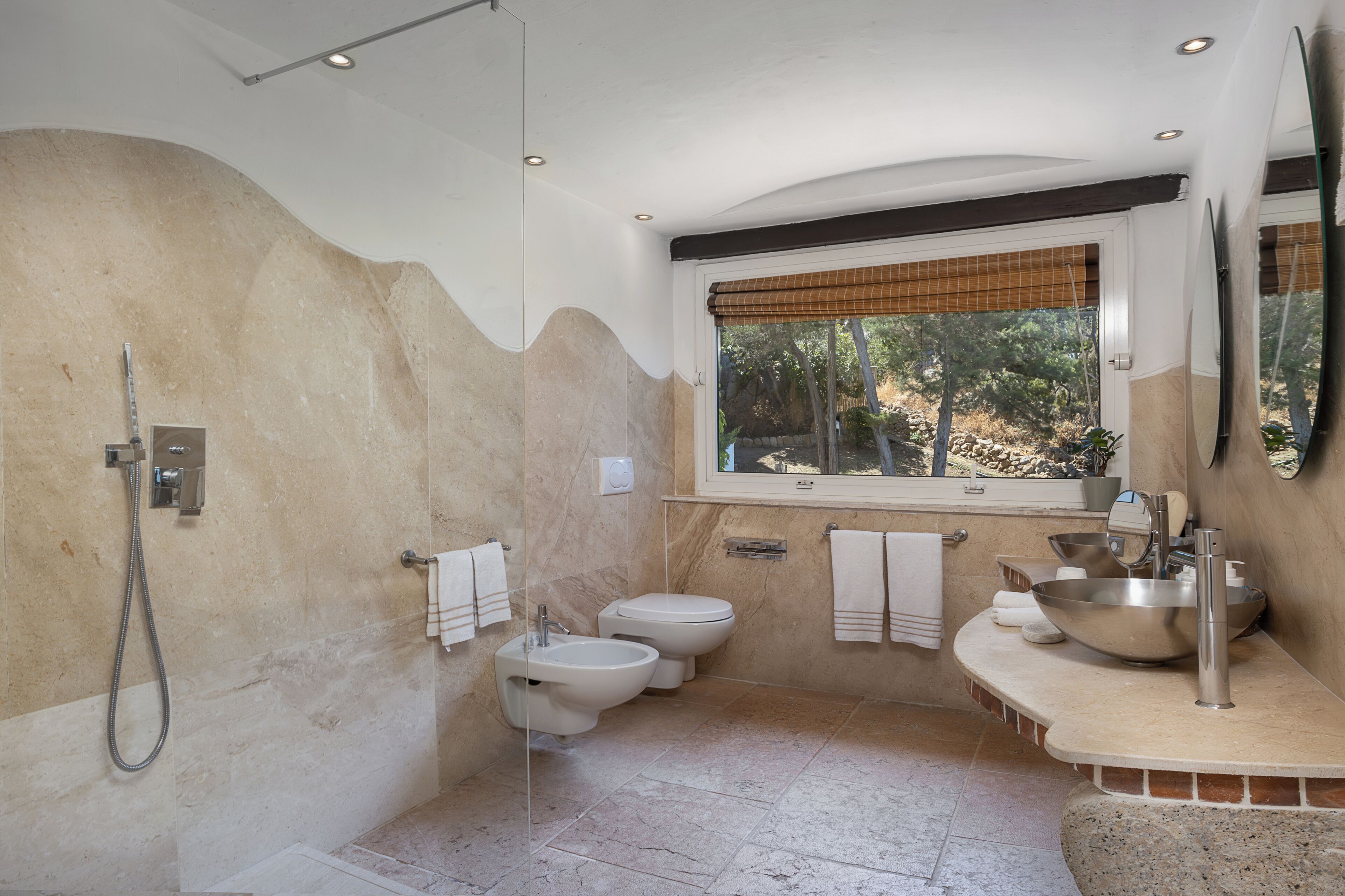 A bathroom with a shower, bidet, toilet, and sink.