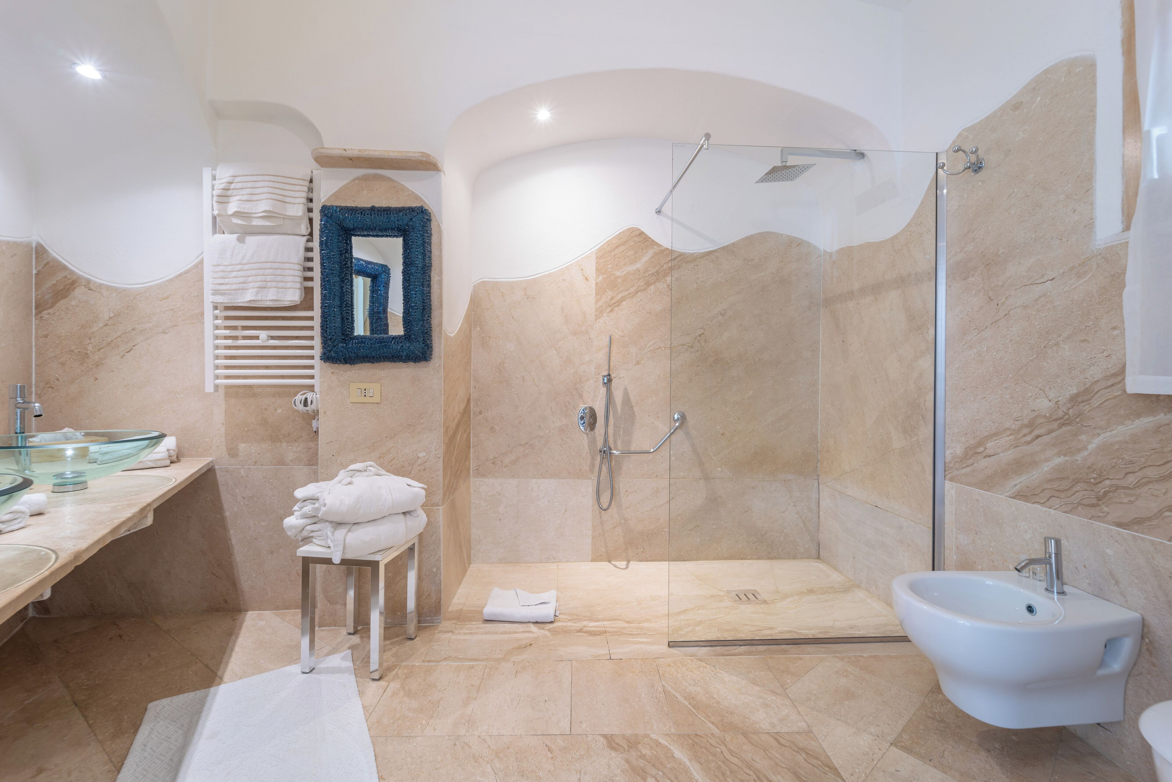 A modern bathroom with a glass-enclosed shower, a bidet, and a vanity with a glass sink.