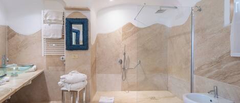 A modern bathroom with a glass-enclosed shower, a bidet, and a vanity with a glass sink.