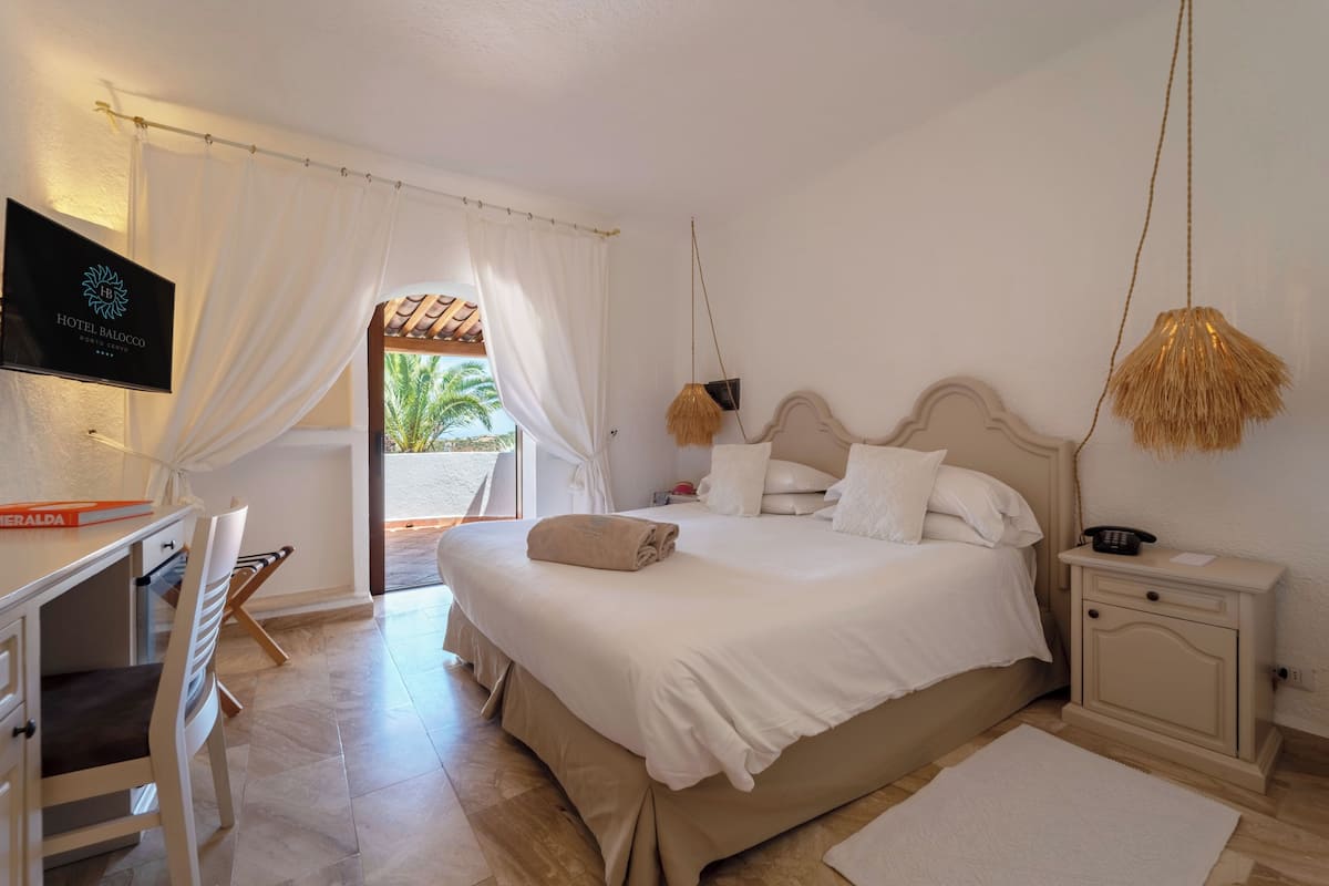 Une chambre d’hôtel équipée d’un lit, d’un bureau, d’une chaise, d’une table de chevet et d’un téléviseur.