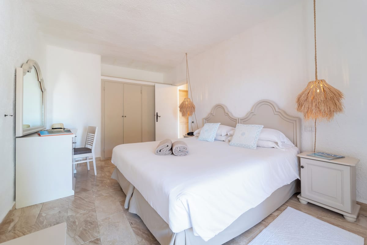 Une chambre bien rangée, avec un grand lit, une table de chevet, une chaise et une armoire.