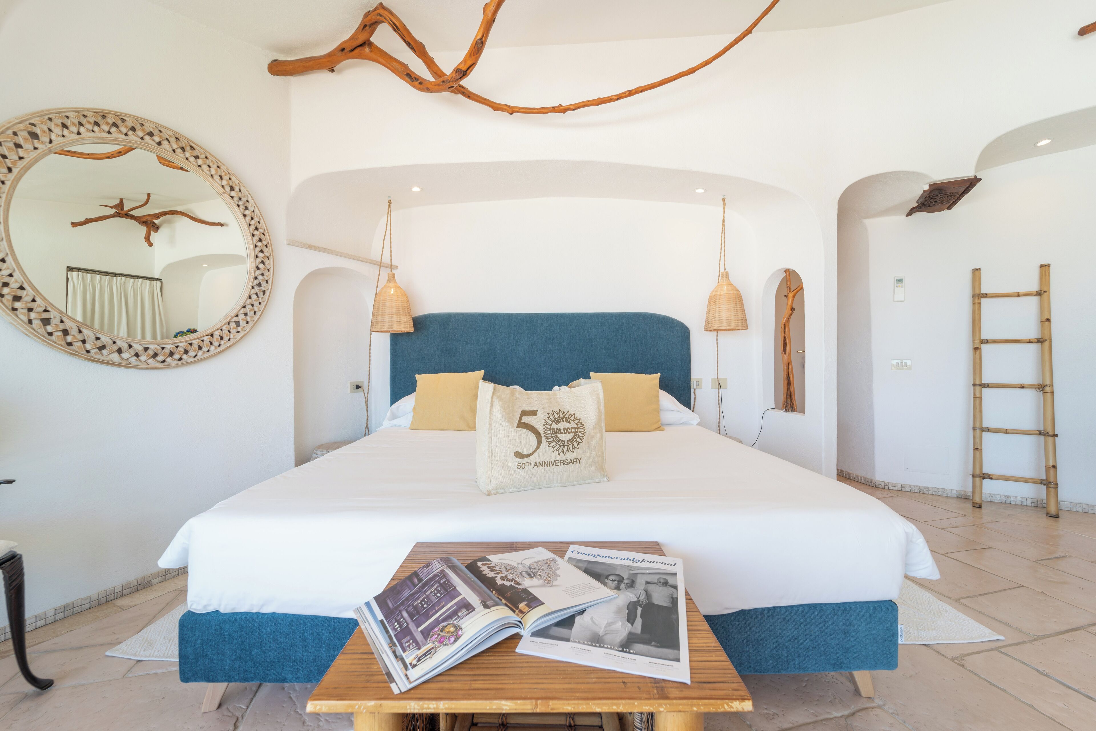 Ein Schlafzimmer mit einem großen Bett, einem Holzkopfteil, einem Spiegel und einem Nachttisch mit Zeitschriften.