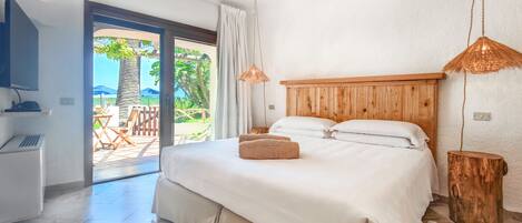 A bedroom with a large bed, a wooden headboard, a TV, and a view of the outdoors.