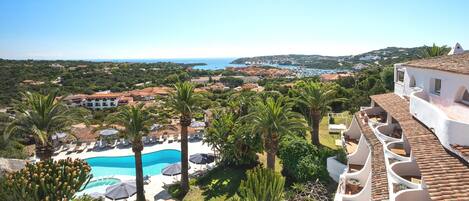 Un resort con piscina, palmeras y vistas a la costa.