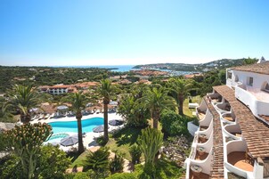 Un resort con piscina, palmeras y vistas a la costa.
