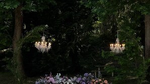 An outdoor wedding venue with white chairs, floral arrangements, and chandeliers. - Grand Hotel Terme (Riolo Terme)