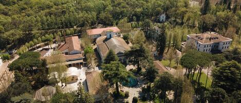 Vista aérea de una finca histórica con varios edificios, un patio central y zonas boscosas circundantes.