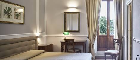 Une chambre à coucher comprenant un lit, un bureau, une chaise, un miroir et donnant sur l’extérieur.