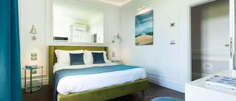 A hotel room with a bed, bedside table, and a desk with a chair.
