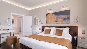 Una habitación de hotel moderna con una cama grande, un escritorio y una silla. Hay un cuadro en la pared y una lámpara en la mesita de noche.